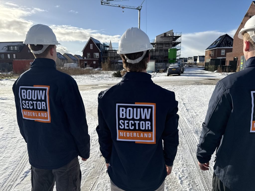 Drie medewerkers van Bouwsector Nederland met witte helm op straat in een nieuwbouwwijk